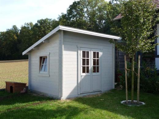 Weißes Gerätehaus mit Pultdach auf Wiese
