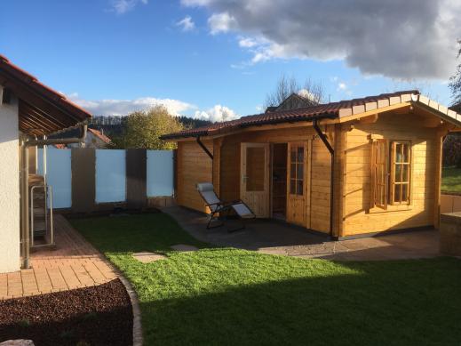 von der Abendsonne beschienenes Saunahaus in Blockohlenbauweise